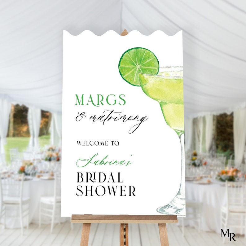 May include: White sign with green and black text that reads "Margs & Matrimony Welcome to Sabrina's Bridal Shower". A green lime wedge and a glass of margarita are illustrated on the sign.