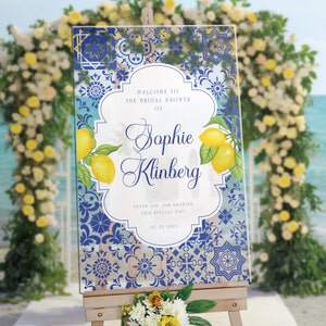 Puede incluir: Un cartel de bienvenida para una despedida de soltera con un patr&oacute;n de azulejos azules y blancos y limones. El cartel dice "Bienvenido a la despedida de soltera de Sophie Klinberg. &iexcl;Gracias por compartir este d&iacute;a especial! 07 23 2024"