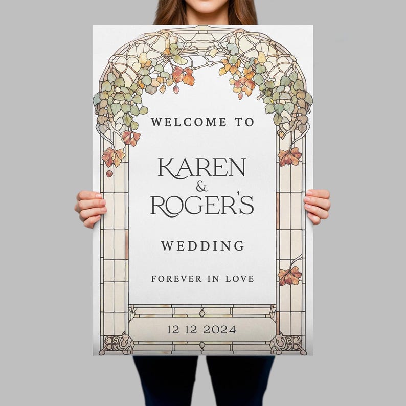 May include: A rectangular wedding sign featuring a stained glass archway design with green and orange foliage. The text reads: WELCOME TO KAREN & ROGER'S WEDDING FOREVER IN LOVE 12 12 2024. The sign has a white background and a grid-like border.