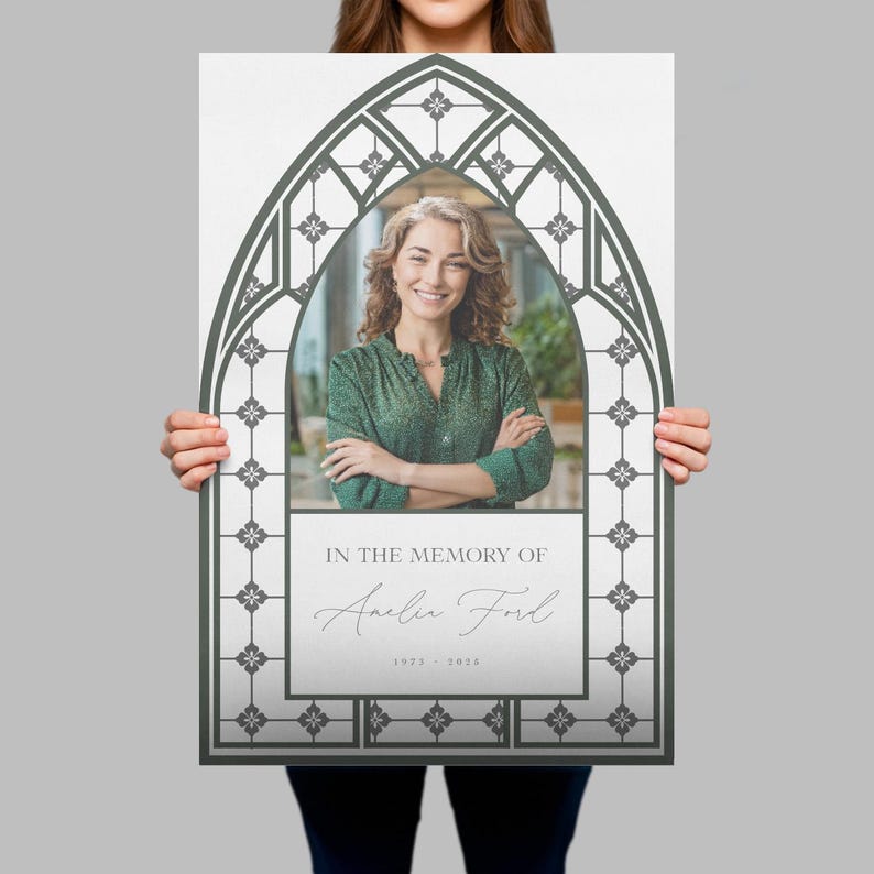 May include: A memorial print featuring a photo of a woman within a gray, arched frame. The text "IN THE MEMORY OF" is above the name "Amelia Ford" and the years "1923 - 2024". The frame has a decorative, stained-glass window design.
