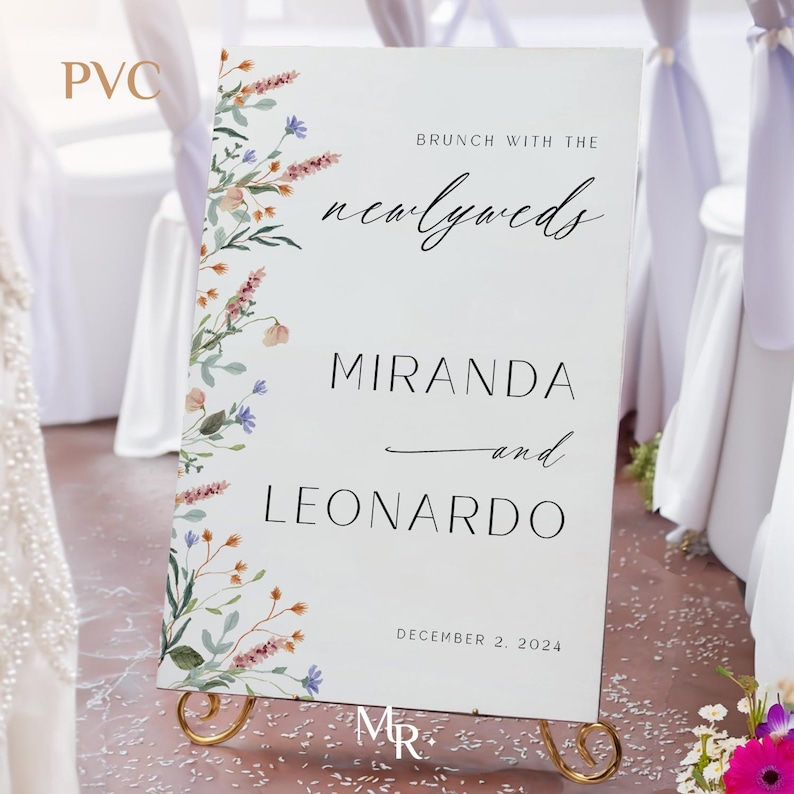 K&ouml;nnte beinhalten: Ein wei&szlig;es Hochzeitsschild mit floralem Rand. Das Schild lautet "Brunch mit den Frischverm&auml;hlten Miranda und Leonardo 2. Dezember 2024".