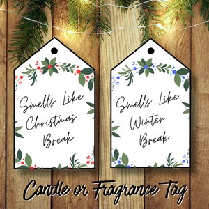 May include: Two white gift tags with a floral border and the text "Smells Like Christmas Break" and "Smells Like Winter Break". The tags are on a wood background with Christmas lights.