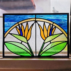 May include: A stained glass window depicting two stylized bird of paradise flowers with yellow, orange, blue, and green glass pieces.
