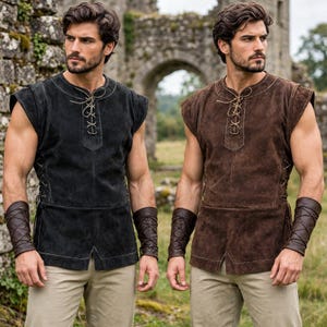 May include: A sleeveless tunic featuring a lace-up front closure and side lacing, paired with matching brown leather forearm bracers. The garment is shown in both black and brown suede-like material, worn over light-coloured trousers.