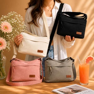 May include: Four crossbody bags in black, cream, pink, and grey. Each bag features a rectangular shape, a top zip closure with a pull tab, an adjustable shoulder strap, and a small brown rectangular patch with the word FASHION printed on it.