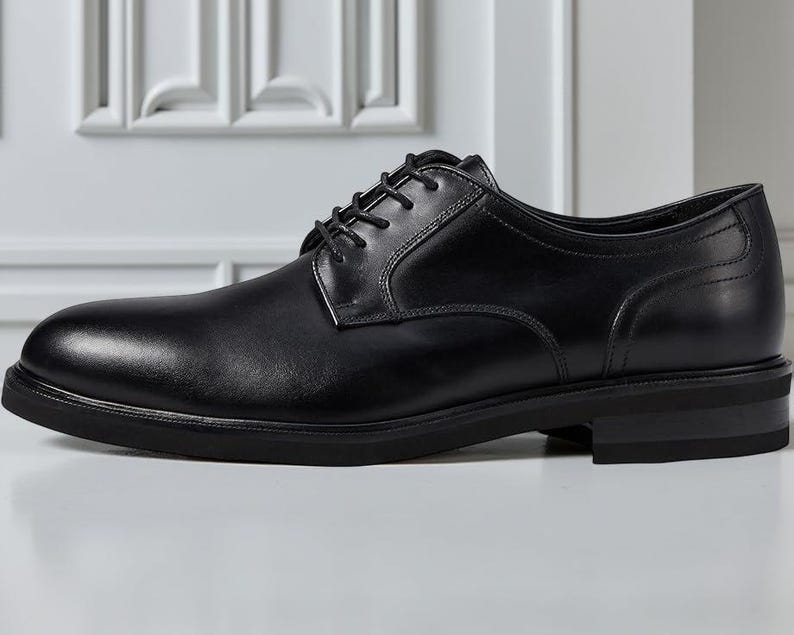 May include: A single black leather dress shoe with a rounded toe and a low heel. The shoe has a lace-up closure and a smooth, polished finish. The shoe is designed for formal occasions.
