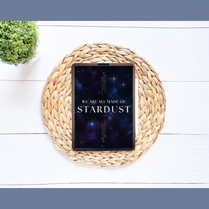 May include: A tablet with a black background and a galaxy design. The text "WE ARE ALL MADE OF STARDUST" is displayed in white on the screen. The tablet is on a woven straw mat.