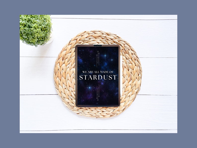 May include: A tablet with a black background and a galaxy design. The text "WE ARE ALL MADE OF STARDUST" is displayed in white on the screen. The tablet is on a woven straw mat.