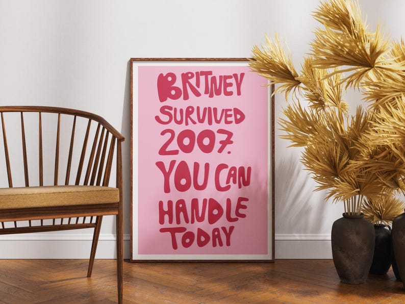 Pink Britney Spears wall art featuring the funny motivational quote “Britney Survived 2007, You Can Handle Today” in bold retro typography. This Y2K-inspired poster has dark pink lettering on a light pink background