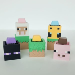 May include: Five Minecraft character figurines with different coloured heads and bodies. The characters are a sheep, a pig, a bee, a creeper, and a Steve. Each character is standing on a green grass block with a brown dirt block underneath.