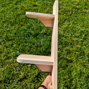 May include: A wooden shelf unit with two shelves. The shelves are made of unfinished wood and have a simple design.