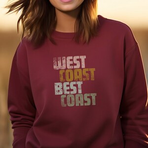 Może przedstawiać: Bordowa bluza z nadrukiem w stylu vintage, kt&oacute;ry głosi "West Coast Best Coast".