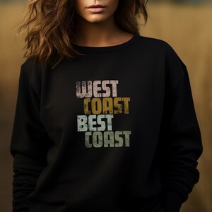 Może przedstawiać: Czarny sweter z nadrukiem w stylu vintage, na kt&oacute;rym widnieje napis "West Coast Best Coast" w kolorowych literach.