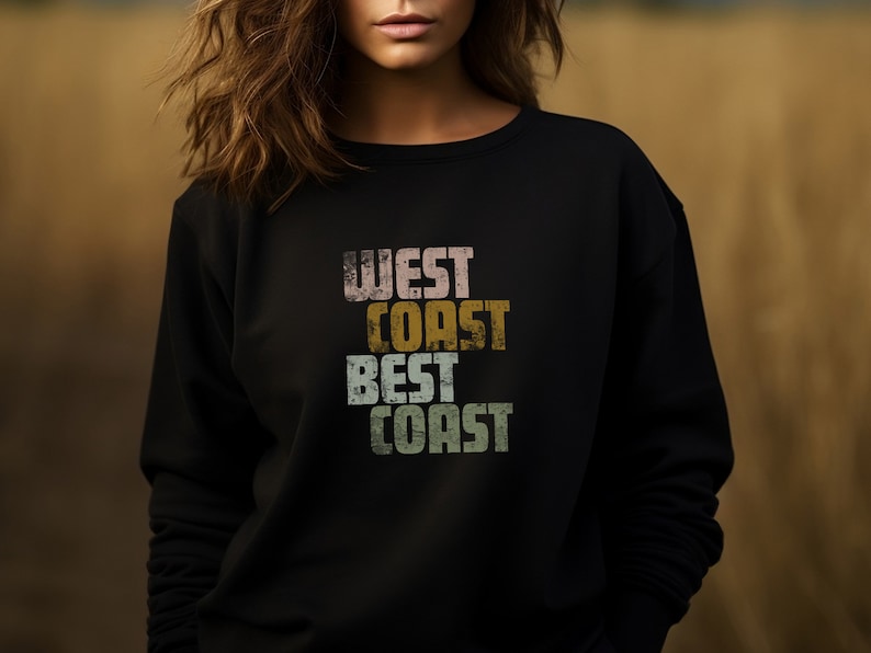 Może przedstawiać: Czarny sweter z nadrukiem w stylu vintage, na kt&oacute;rym widnieje napis "West Coast Best Coast" w kolorowych literach.