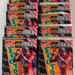 Könnte beinhalten: Versiegelte Packungen mit NFL-Footballkarten von Upper Deck Collector's Choice aus dem Jahr 1996. Jede Packung zeigt einen Footballspieler in roter Uniform. Die Packungen tragen das NFL-Logo und die Aufschrift "Collector's Choice". Jede Packung enthält Bonuskarten.