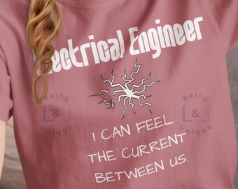 May include: A pink t-shirt with the text "Electrical Engineer" and a stylized lightning bolt graphic. The text "Being L&J Unique" appears twice on the shirt, once on each side of the graphic. The text "I can feel the current between us." is printed below the graphic.