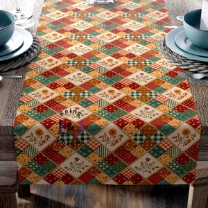 May include: A colorful table runner with a patchwork design. The runner features a diamond pattern with squares of red, green, yellow, and beige fabric. Floral and gingham patterns are incorporated into the design. The text "Being L&J Unique" is visible.
