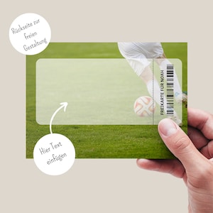 Puede incluir: Un boleto de f&uacute;tbol verde y blanco con el texto "FREIKARTE F&Uuml;R NOAH" impreso en &eacute;l. El boleto se sostiene en una mano contra un fondo de hierba verde con un jugador de f&uacute;tbol en el fondo.