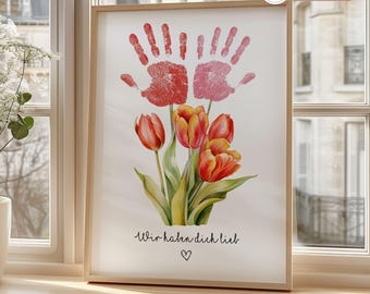 Könnte beinhalten: Ein weißer gerahmter Druck mit zwei rosa Handabdrücken über einem Strauß orangefarbener Tulpen. Der Druck hat den Text "Wir haben dich lieb" und ein kleines Herz.