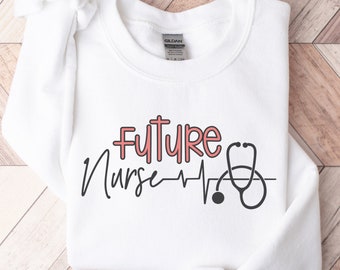 Könnte beinhalten: Weißer Pullover mit dem Text "Future Nurse" in Rosa und Schwarz mit einer Stethoskopgrafik.