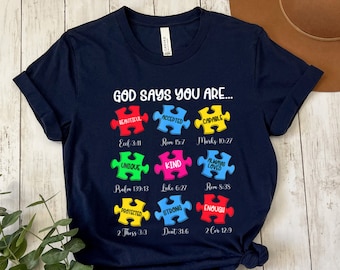 May include: Navy blue t-shirt with a graphic of puzzle pieces that say "God says you are..." with bible verses and words like "beautiful", "accepted", "capable", "unique", "kind", "loved", "protected", "strong", and "enough".
