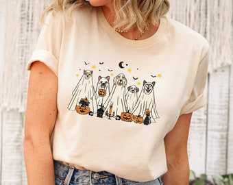May include: A cream-colored t-shirt with a graphic of five dogs dressed as ghosts for Halloween. The dogs are holding pumpkins and candy. The graphic is in a vintage style.