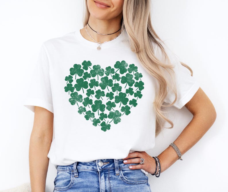 May include: White t-shirt with a green shamrock heart design. The shamrocks are arranged in a heart shape.