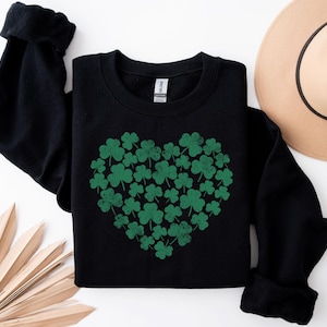 May include: Black sweatshirt with a green shamrock heart design. The shamrocks are arranged in a heart shape.