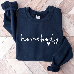 May include: A navy blue sweatshirt with the word "homebody" written in white cursive lettering and a small white heart.