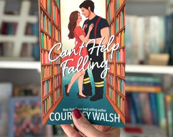 May include: A book cover with the title "Can't Help Falling" featuring a couple embracing in front of a bookshelf. The cover art has a romantic theme. The author's name, Courtney Walsh, is also visible.