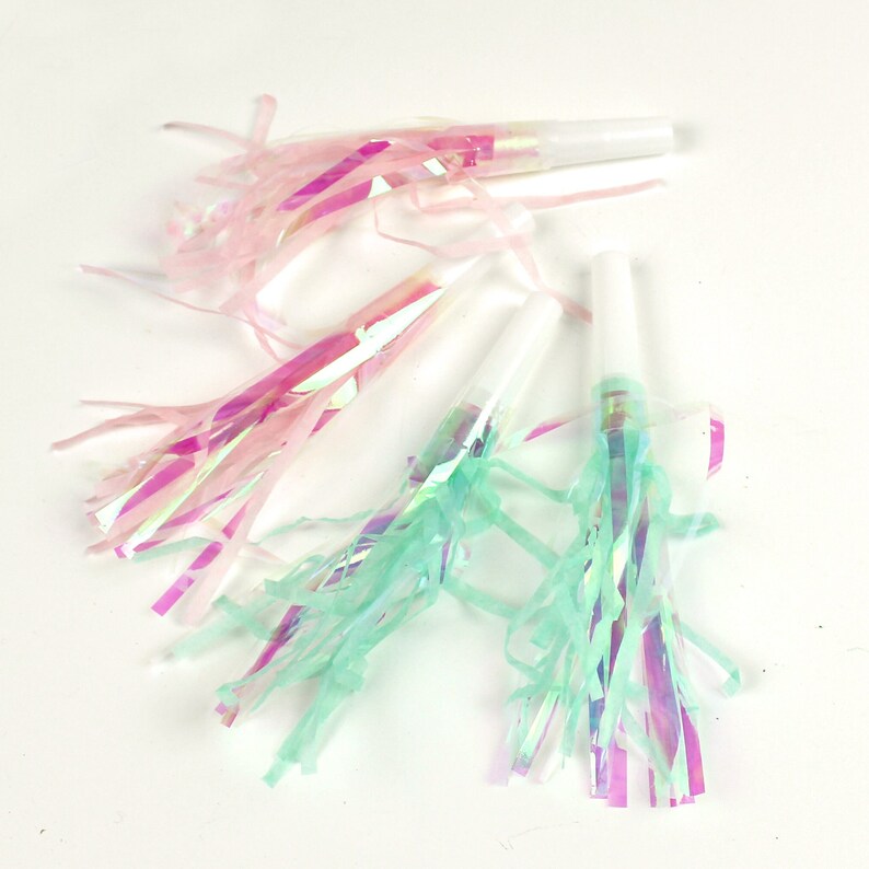 May include: A set of party blowers with iridescent pink and green streamers. The blowers are white and have a simple design.