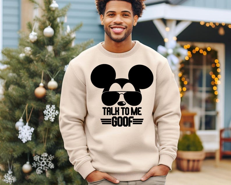 May include: A beige crewneck sweatshirt featuring a black graphic of Mickey Mouse wearing sunglasses. Below the graphic, the text reads TALK TO ME GOOF in a bold, stylized font with horizontal lines flanking the word GOOF on both sides.