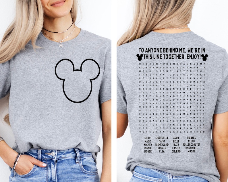 K&ouml;nnte beinhalten: Ein hellgraues T-Shirt mit einer schwarzen Umrisszeichnung von Mickey Mouse's Kopf auf der Vorderseite. Auf der R&uuml;ckseite steht der Text "TO ANYONE BEHIND ME, WE'RE IN THIS LINE TOGETHER. ENJOY!" und ein Disney-Wortsuchr&auml;tsel.