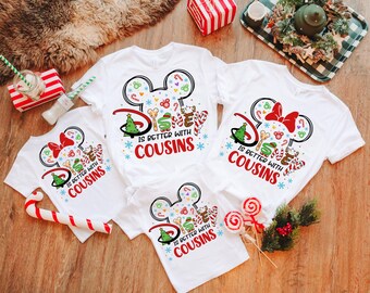 May include: Four white t-shirts with a Christmas-themed Mickey Mouse design. The shirts feature a red bow, a green Christmas tree, and the text "Disney is better with cousins".