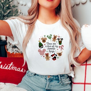 May include: White t-shirt with a Christmas-themed design featuring Mickey Mouse, gingerbread cookies, candy canes, and the text "These are a few of my favorite things."