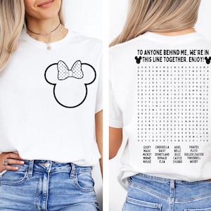K&ouml;nnte beinhalten: Wei&szlig;es T-Shirt mit einem schwarz-wei&szlig;en Minnie Mouse-Design auf der Vorderseite. Auf der R&uuml;ckseite des Shirts befindet sich ein Wortsuchr&auml;tsel mit Disney-Charakternamen und dem Text: "TO ANYONE BEHIND ME, WE'RE IN THIS LINE TOGETHER. ENJOY!"