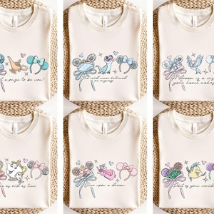 Puede incluir: Camisetas color crema con gr&aacute;ficos de dibujos animados coloridos y texto. Los dise&ntilde;os incluyen personajes, lazos y frases como "I'm not a prize to be won!" y "Tale as old as time." Las camisetas son probablemente para fans de pel&iacute;culas de animaci&oacute;n.