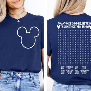 K&ouml;nnte beinhalten: Marineblaues T-Shirt mit wei&szlig;em Mickey Mouse-Umriss auf der Vorderseite. Auf der R&uuml;ckseite des Shirts steht der Text "TO ANYONE BEHIND ME, WE'RE IN THIS LINE TOGETHER. ENJOY!" und ein Disney-Charakter-Suchr&auml;tsel.