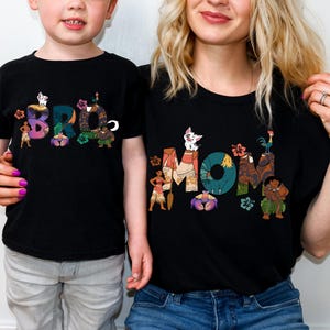 May include: Matching black t-shirts featuring a graphic design of characters from the film Moana. The adult shirt says "MOM" and the child's shirt says "BRO".