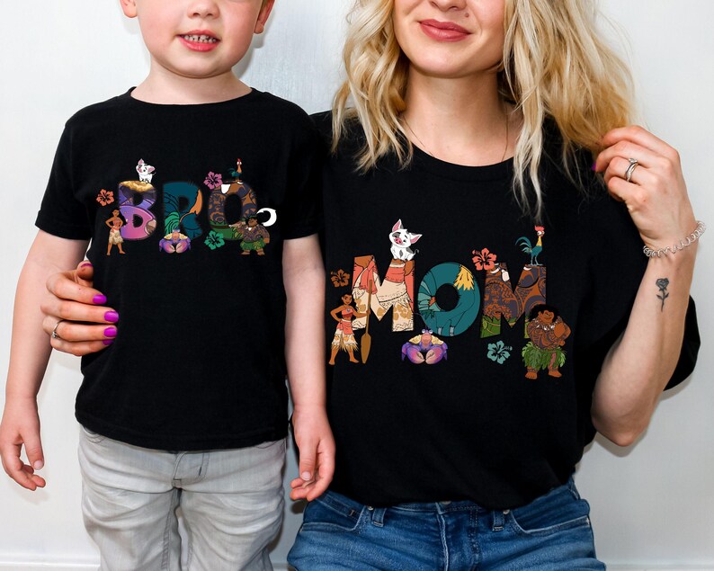 May include: Matching black t-shirts featuring a graphic design of characters from the film Moana. The adult shirt says "MOM" and the child's shirt says "BRO".