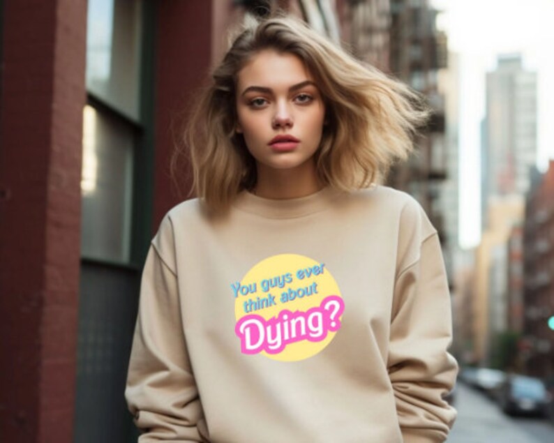 May include: A beige sweatshirt with a yellow circle graphic that says "You guys ever think about Dying?" in blue and pink text.