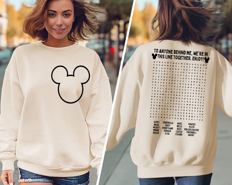 K&ouml;nnte beinhalten: Cremefarbenes Sweatshirt mit schwarzer Umrisszeichnung von Mickey Mouse auf der Vorderseite. Auf der R&uuml;ckseite befindet sich ein Suchsel mit Disney-Charakternamen und dem Text: "TO ANYONE BEHIND ME, WE'RE IN THIS LINE TOGETHER. ENJOY!"
