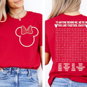 K&ouml;nnte beinhalten: Rotes T-Shirt mit wei&szlig;em Minnie Mouse-Design auf der Vorderseite. Auf der R&uuml;ckseite steht der Text "TO ANYONE BEHIND ME, WE'RE IN THIS LINE TOGETHER. ENJOY!" und ein Disney-Wortsuchr&auml;tsel.