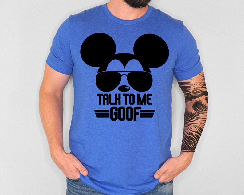 May include: A royal blue short-sleeve t-shirt featuring a black graphic of a mouse silhouette wearing sunglasses. Below the graphic, the text reads "TALK TO ME GOOF" in bold black capital letters, flanked by two horizontal lines on each side.