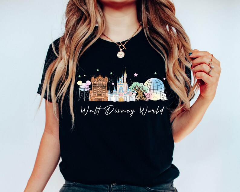 May include: Black t-shirt featuring a colorful illustration of the Walt Disney World skyline. The design includes iconic landmarks like Cinderella Castle, Spaceship Earth, and the Tower of Terror, with the words "Walt Disney World" in a script font.