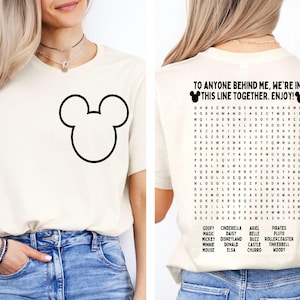 K&ouml;nnte beinhalten: Cremefarbenes T-Shirt mit einer gro&szlig;en schwarzen Mickey Mouse-Umrisslinie auf der Vorderseite. Auf der R&uuml;ckseite des Shirts steht der Text "TO ANYONE BEHIND ME, WE'RE IN THIS LINE TOGETHER. ENJOY!" und ein Disney-Wortsuchr&auml;tsel.