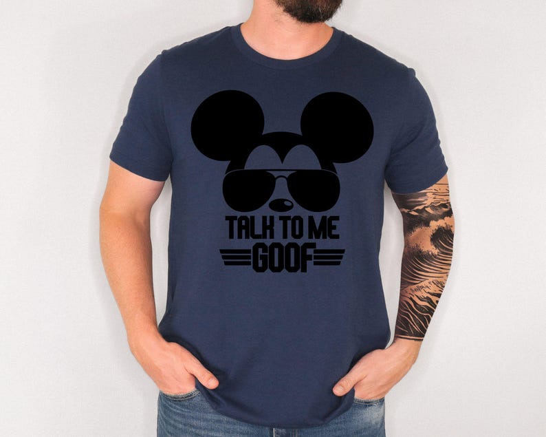 May include: A navy blue short-sleeved t-shirt featuring a black graphic of a mouse silhouette wearing sunglasses. Below the graphic, the text reads TALK TO ME GOOF in bold black capital letters, flanked by two horizontal lines on each side.