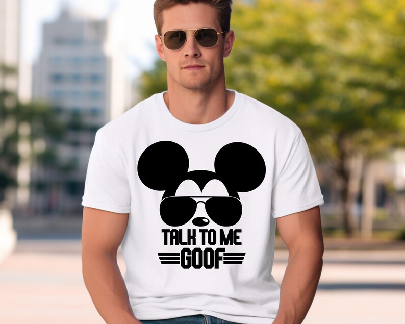 May include: A white short-sleeved t-shirt featuring a black graphic of a mouse silhouette wearing sunglasses. Below the graphic, the text reads TALK TO ME GOOF in bold black capital letters, flanked by two horizontal black lines on each side.