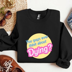 May include: Black sweatshirt with a yellow circle and the text "You guys ever think about Dying?" in pink and blue letters.