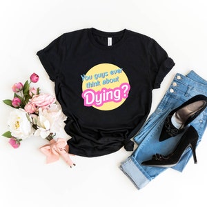 May include: Black t-shirt with a yellow circle and the text "You guys ever think about Dying?" in pink and blue letters.
